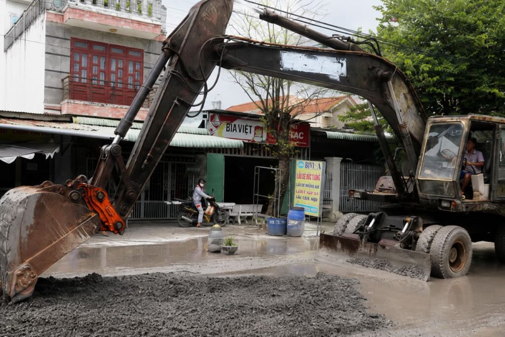 Máy xúc sửa chữa mặt đường Bưng Môn bị hư hỏng do xe tải vận chuyển vật liệu thi công.