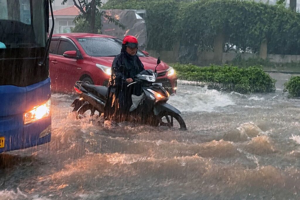 Mưa lớn khiến nhiều tuyến đường ở Đồng Nai ngập sâu, xe cộ khó di chuyển, người dân phải dắt xe qua vùng nước.